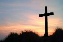 a cross on a hill at sunset